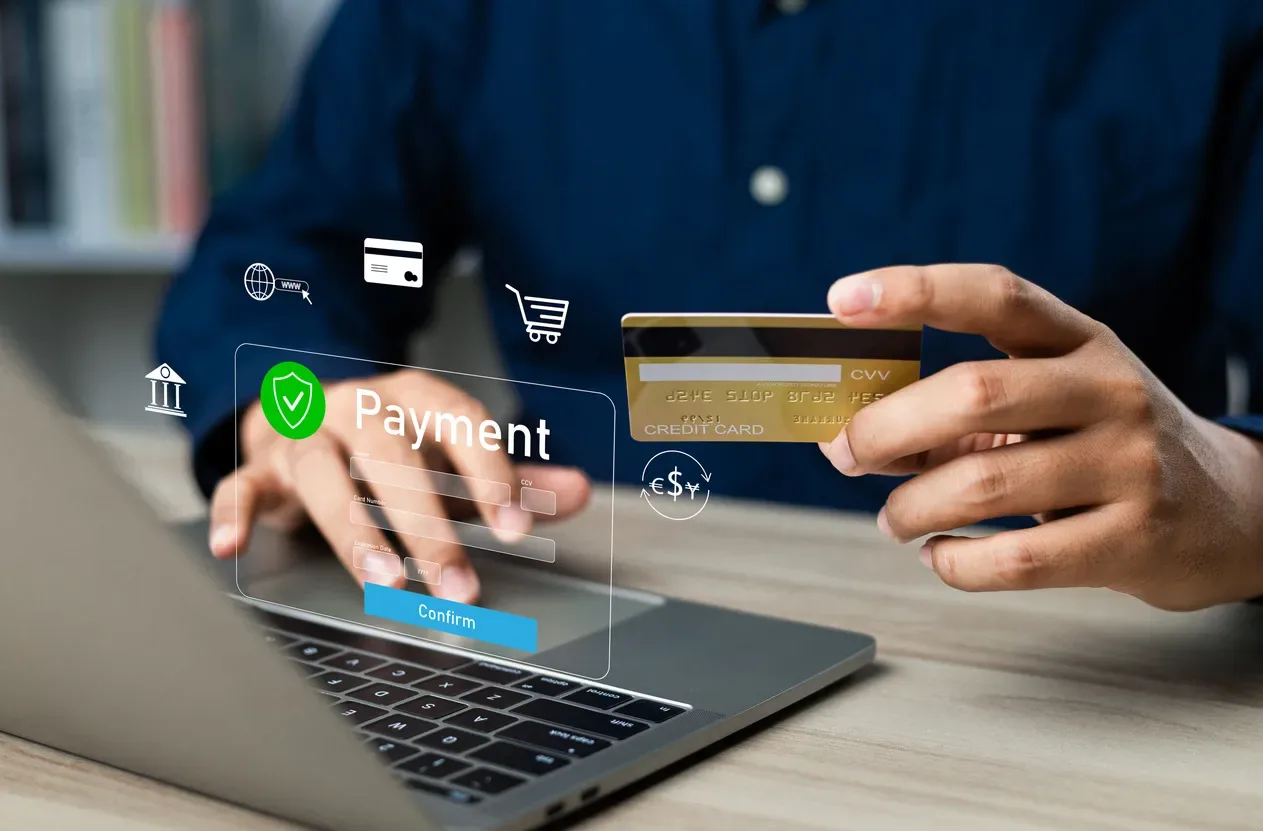 Payment form with card fields and a confirm button beside a laptop and a bank card